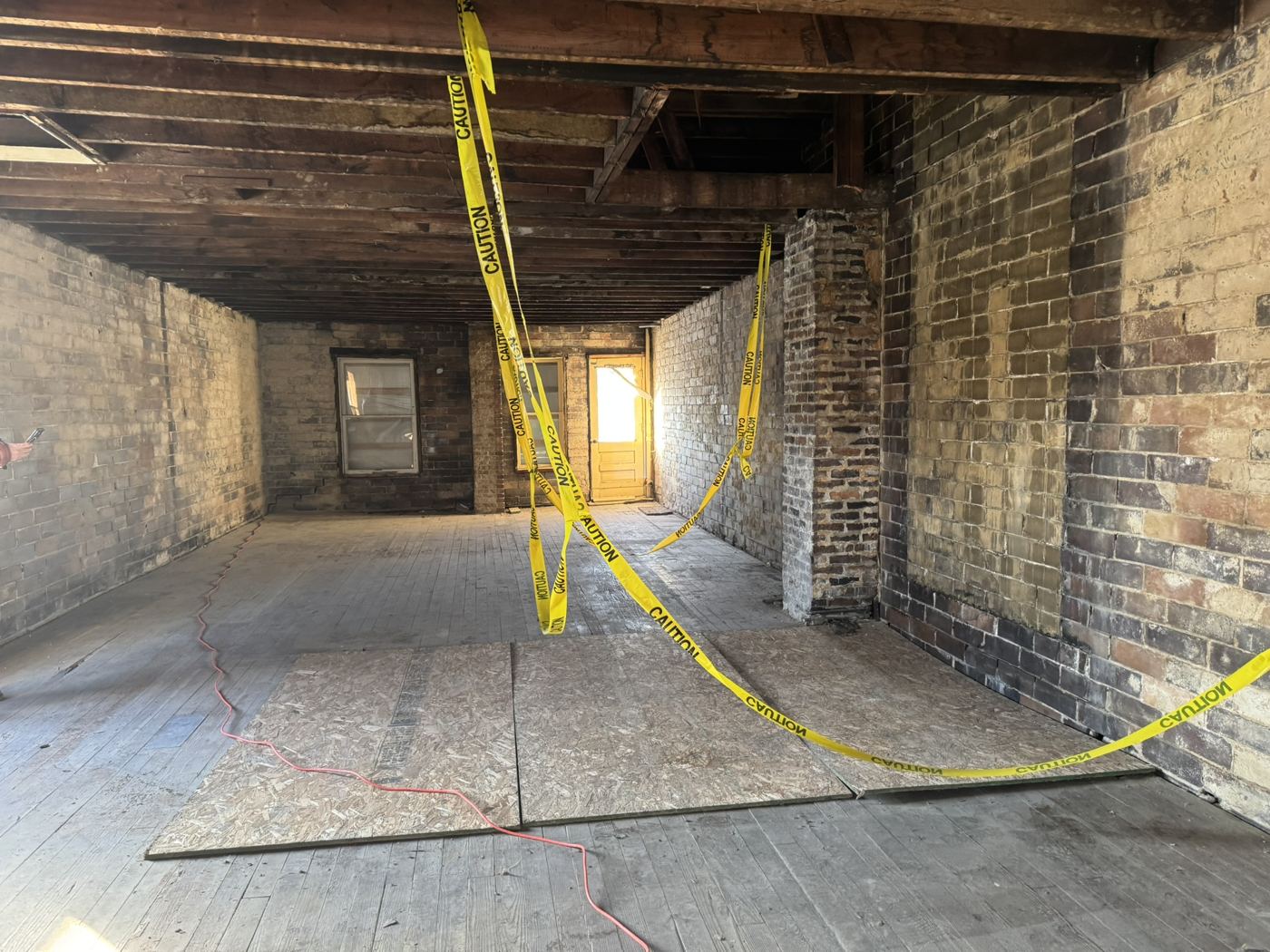 Interior with exposed brick and joists before renovation